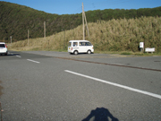 絆の鐘と、道路を挟んだ山側が駐車場